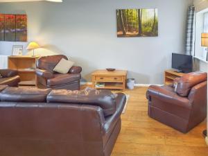 a living room with two leather couches and a television at Cowslip Cottage- W43122 in Goxhill