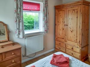 a bedroom with a bed and a dresser and a window at Cowslip Cottage- W43122 in Goxhill