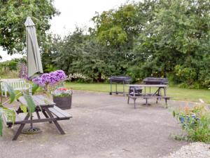 Goxhill的住宿－Cowslip Cottage- W43122，一组野餐桌、雨伞和鲜花