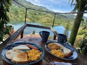 - une table avec deux assiettes de petit-déjeuner avec vue dans l'établissement Glamping Cottage Master Room en Guatapé-Desayuno, à Chiquinquirá