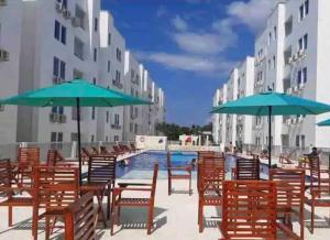 einen Pool mit Tischen, Stühlen und Sonnenschirmen in der Unterkunft Genial apartamento de playa! coveñas in Coveñas