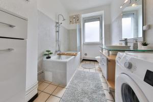ein Badezimmer mit einer Badewanne, einem Waschbecken und einer Waschmaschine in der Unterkunft LE CITADIN - CENTRE VILLE - MUSEE AUTOMOBILE - Parc EXPO in Mulhouse