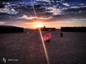 eine Person, die auf einem Feld mit Sonnenuntergang im Hintergrund steht in der Unterkunft Apadi camp in Bucht von Coraya