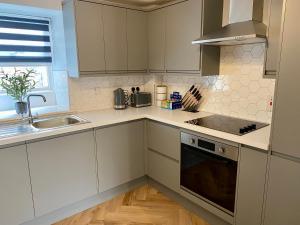 a kitchen with white cabinets and a sink at Luxury Riverside City Centre Apartment in York
