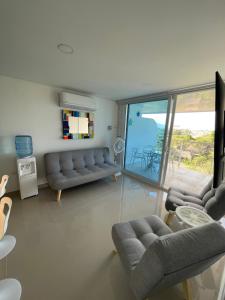 a living room with couches and a sliding glass door at Infinity Blue - Playa Dormida in Santa Marta