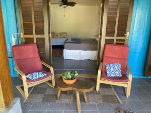 un portico con due sedie, un tavolo e un letto di Casa da Ilha do Mel - Pousada de Charme a Ilha do Mel