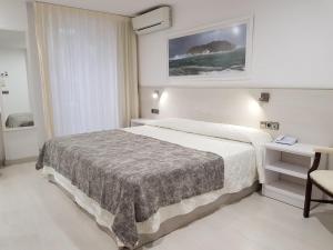 a hotel room with a bed and a table and a chair at Hotel Santa Anna in L'Estartit