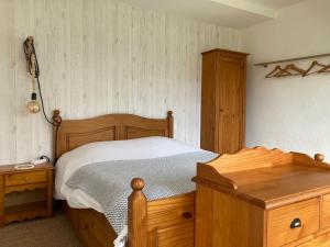 um quarto com uma cama de madeira e uma cómoda de madeira em Gîte La Maison de JuJu em Lacave