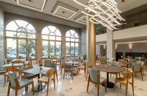 een restaurant met tafels en stoelen en een kroonluchter bij Hotel Lefkas in Lefkada