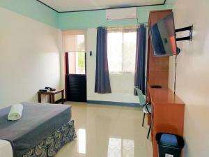 a bedroom with a bed and a television and a desk at E & C Hotel in Laoag