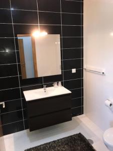 a black tiled bathroom with a sink and a mirror at Restaurante Residencial Pizzaria S. Estevão in Aguiar da Beira +24 photos