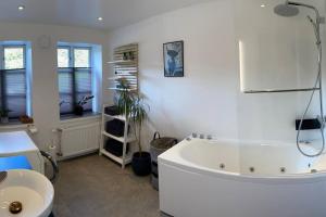 a white bathroom with a tub and a sink at Naturskøn landidyl på Ibækgaarden - I egen bolig in Vejle