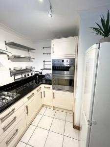 een keuken met witte kasten en een roestvrijstalen koelkast bij Beautiful 2 bedroom garden flat w/ free parking in Surbiton