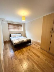 Schlafzimmer mit einem Bett und Holzboden in der Unterkunft Beautiful 2 bedroom garden flat w/ free parking in Surbiton