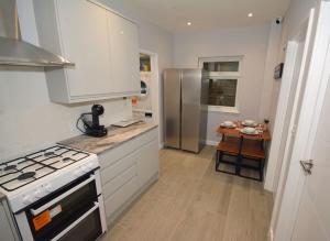 uma cozinha com armários brancos e um frigorífico de aço inoxidável em Walton Suites em Watford