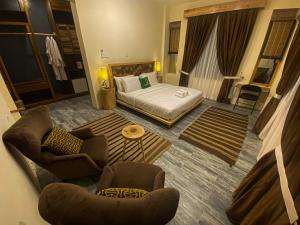 um quarto de hotel com uma cama, um sofá e cadeiras em Dumani Nagar Hotel & Resort em Hunza