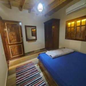 een slaapkamer met een blauw bed en een spiegel bij Boondok's house in Dahab