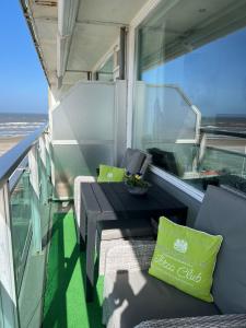 a balcony with a couch and a green pillow on it at Apartment Fleurette in Zandvoort