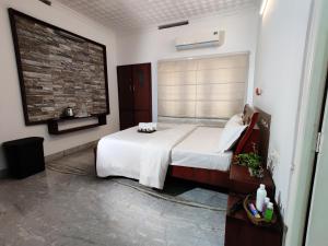 a bedroom with a white bed and a brick wall at The Nook Home in Ernakulam