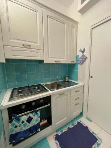 a kitchen with white cabinets and a stove and a sink at Villa ValePina in Villasimius