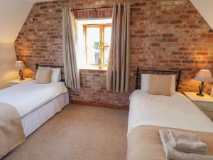 2 Betten in einem Zimmer mit Ziegelwand in der Unterkunft The Granary in Louth