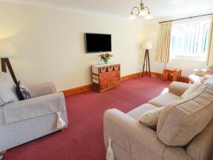sala de estar con 2 sofás y TV de pantalla plana en Nursery Cottage, en Louth