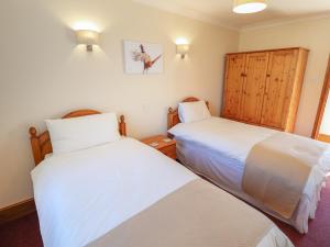 dwa łóżka w pokoju z białą pościelą w obiekcie Nursery Cottage w mieście Louth