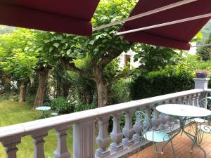 a balcony with a table and chairs and an umbrella at CASTEL MT Villa spacieuse Luchon vue montagnes Pyrénées in Luchon