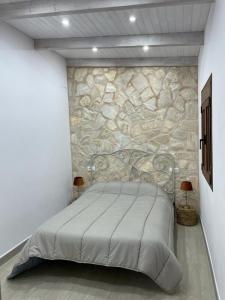 uma cama num quarto com uma parede de pedra em Vivienda turística Las 3 A em El Ojuelo