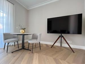 ein Wohnzimmer mit einem Tisch und einem Großbild-TV in der Unterkunft Luxury Home / 2-Raum-Apartment an der Frauenkirche in Dresden