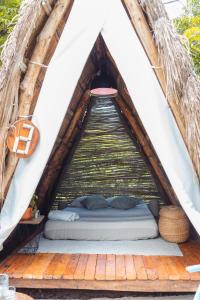 a bed in a tent with a wooden deck at Santuario Beach Hostel in Tierra Bomba