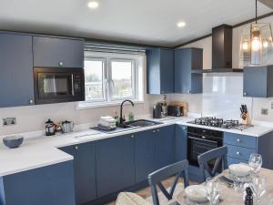 een keuken met blauwe kasten en een tafel met stoelen bij Dodd - Uk42499 in Bassenthwaite