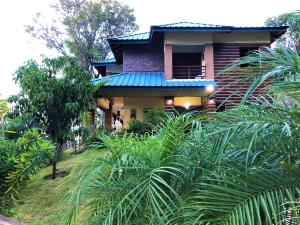 une maison avec un toit bleu et quelques palmiers dans l'établissement Green Village By Hospedify, Hermosa Villa En Las Alturas con Piscina, Billar, y BBQ, à Jarabacoa