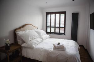 Schlafzimmer mit einem weißen Bett und einem Fenster in der Unterkunft •MangoHausLondon• •airconditioned•garden•fire pit• in London