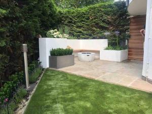 un jardín con un banco en medio de un patio en •MangoHausLondon• •airconditioned•garden•fire pit•, en Londres