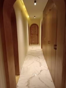 a hallway with a white marble floor and wooden doors at Ground floor apartment at October Plaza by Sodic in Madīnat Sittah Uktūbar