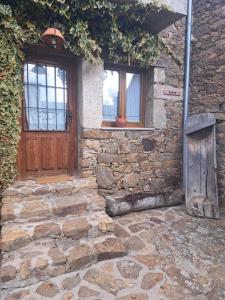 ein Steinhaus mit einer Holztür und zwei Fenstern in der Unterkunft Casa Rural La Pantizuela 