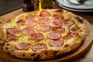a pepperoni pizza sitting on top of a wooden table at Transamerica Executive Belo Horizonte in Belo Horizonte
