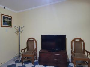 sala de estar con 2 sillas y TV de pantalla plana en Lo De Mir en Salta
