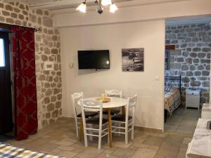 una sala da pranzo con tavolo, sedie e TV di Myral Guesthouse a Nauplia