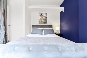 a bedroom with a large white bed with blue walls at Leafy Oasis Wandsworth Chic Pad in London