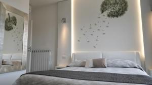 a white bedroom with a bed and a wall with butterflies at La Brise in Marina di Pietrasanta