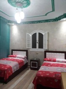 a bedroom with two beds with red sheets and a ceiling at Rental apartment at Ras El Bar City in ‘Izbat al Jirabī