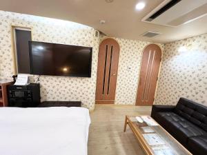 sala de estar con cama y TV de pantalla plana en HOTEL MINT HOUSE -resort and relaxation- en Mihama