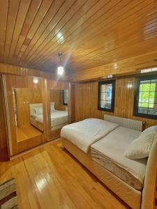 sypialnia z 2 łóżkami w pokoju z drewnianymi ścianami w obiekcie Helen Suit w mieście Çaykara