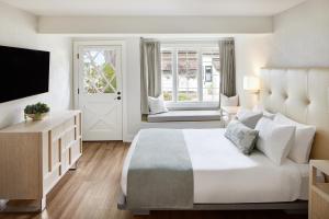 a white bedroom with a large bed and a television at Green Gables Inn, A Four Sisters Inn in Pacific Grove