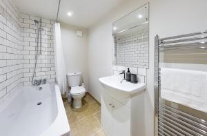 a bathroom with a sink and a toilet and a tub at Redhill town centre apartments by Livingo in Redhill