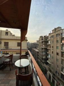 uma varanda com uma mesa, cadeiras e edifícios em Cairo House Hostel no Cairo