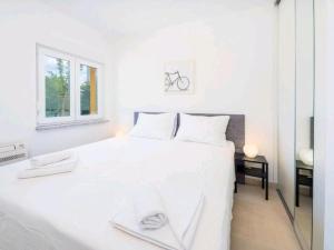 biała sypialnia z białym łóżkiem i oknem w obiekcie Adriatico w mieście Omišalj