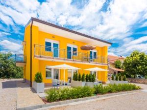 żółty dom z balkonem i parasolami w obiekcie Adriatico w mieście Omišalj